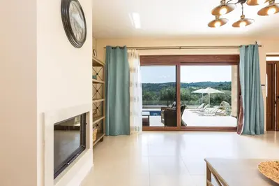 a living room with a fireplace and a television at Rodi Stone Villa in Kalyves