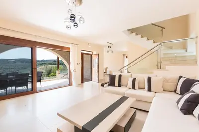 a living room with a white couch and a table at Levanda Luxury Stone Villa in Kalyves