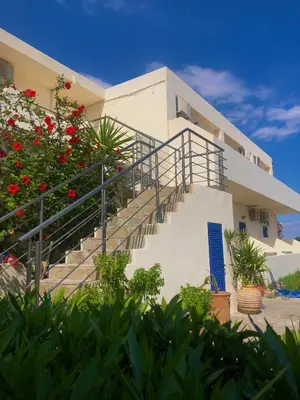 a building with stairs and flowers in front of it at Flisvos Rooms in Frangokastello