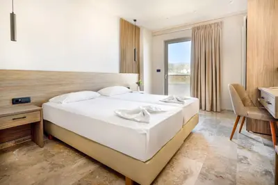 a bedroom with a large white bed and a desk at Elena Beach Hotel in Kissamos