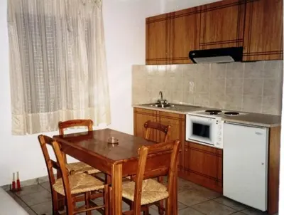 a kitchen with a table and chairs and a white refrigerator at Flisvos Apartments in Frangokastello