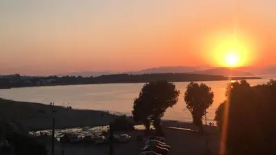 a sunset over a large body of water with trees at Kleanthi Studios in Chania Town