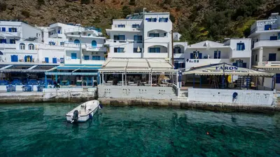 a boat in the water in front of buildings at Kyma in Loutro