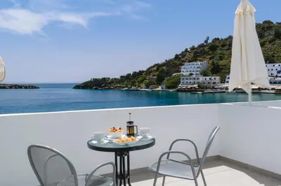 a table on a balcony with a view of the ocean at Kyma in Loutro