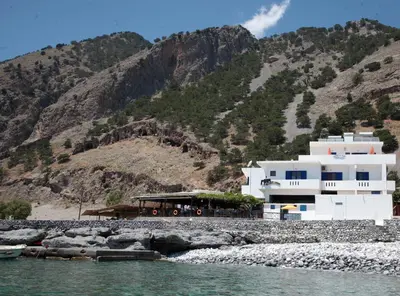 a building on the shore of a body of water at Paralia guest house in Agia Roumeli