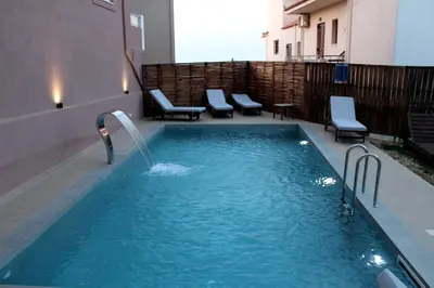 a pool with a water fountain in a building at Mithos Premium Rooms in Agia Marina Nea Kydonias