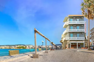 a hotel on the beach with palm trees and a building at Kumba At Koum Kapi in Chania Town