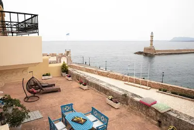 a patio with a view of the ocean and a lighthouse at Revellino del Porto, Historic Residence in Chania Town
