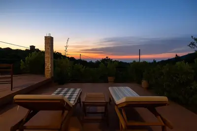 a patio with two benches and a table and a sunset at Sofiana's Garden Retreat with Private Pool in Drapaniás
