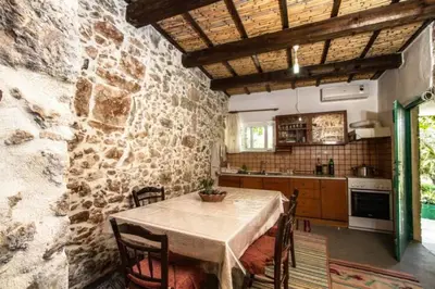 a kitchen with a table and a stone wall at Sofiana's Garden Retreat with Private Pool in Drapaniás