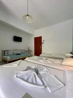 a room with three beds and a tv on a wall at Panorama Rooms in Agia Roumeli