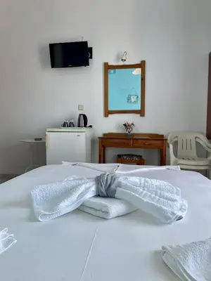 a white bed with towels on it with a television at Panorama Rooms in Agia Roumeli