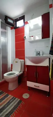 a red and white bathroom with a toilet and a sink at Elia Guesthouse - Kissamos in Kissamos