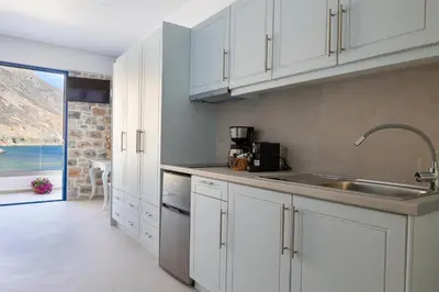 a kitchen with white cabinets and a sink at Molos Apartments in Loutro