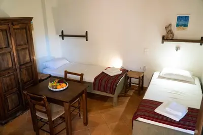 a room with two beds and a table with a bowl of fruit at Arhondiko in Sougia