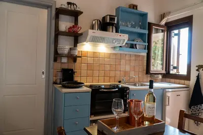 a kitchen with blue cabinets and a bottle of wine at Arhondiko in Sougia