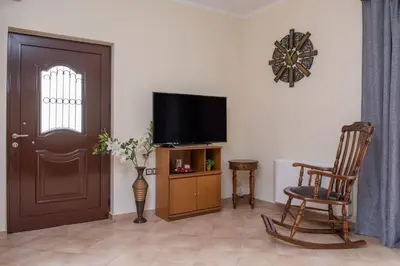 a living room with a television and a rocking chair at Marika Traditional Home in Élos