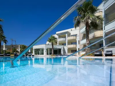 a swimming pool in front of a building with palm trees at Molos Bay Hotel in Kissamos