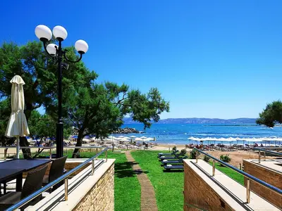 a beach with a street light and tables and umbrellas at Molos Bay Hotel in Kissamos