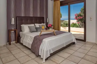 a bedroom with a bed and a table with flowers on it at Cretan Blu Platanias in Plataniás