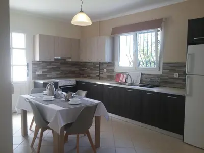 a kitchen with a table with a white table cloth at Maria's Garden in Galatás
