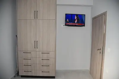 a bedroom with wooden cabinets and a tv on a wall at Pirgos Deluxe Apartment - Private Parking in Kissamos