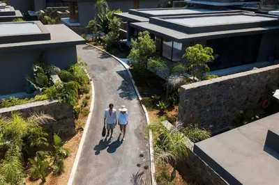 two people walking down a road in front of a house at Domes Zeen Chania, a Luxury Collection Resort, Crete in Kato Daratso
