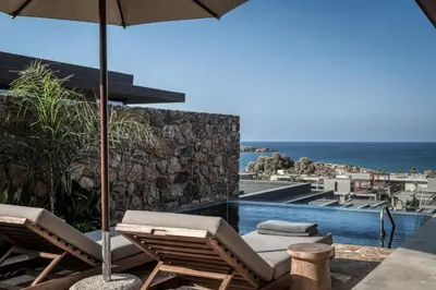 a swimming pool with two lounge chairs and an umbrella at Domes Zeen Chania, a Luxury Collection Resort, Crete in Kato Daratso