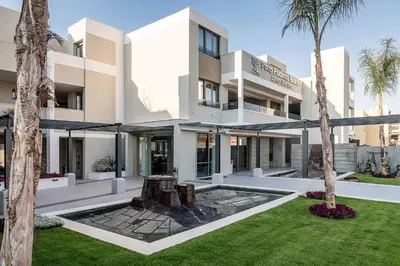 a large white building with palm trees in front of it at Porto Platanias Beach Luxury Selection - Adults Only in Plataniás