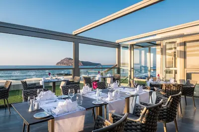 a restaurant with tables and chairs with a view of the ocean at Porto Platanias Beach Luxury Selection - Adults Only in Plataniás