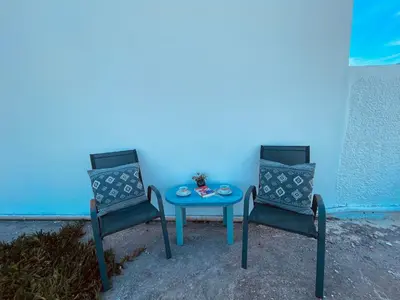 two chairs and a table in front of a blue wall at Brina's House in Kissamos