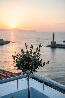 a tree in front of the ocean at sunset at Alexandra's Lighthouse View in Chania Town