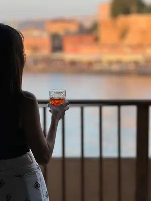 a woman holding a drink in her hand at Captain Vasilis Hotel in Chania Town