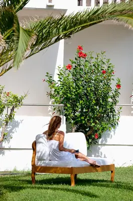a woman sitting on a bed in the grass at Mrs Chryssana Beach Hotel in Kolymvari