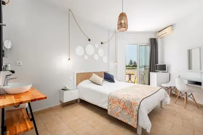 a bedroom with a bed and a sink and a bathroom at Mrs Chryssana Beach Hotel in Kolymvari