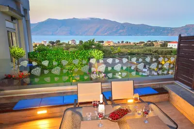 a balcony with a table and chairs and a view of the ocean at Villa Zafyra in Kissamos