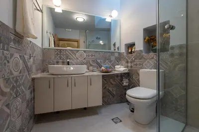 a bathroom with a sink and a toilet and a mirror at Villa Theta With Private Pool by Amara Living in Drapaniás