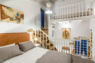 a white bedroom with a bed and a staircase at Elvie House in Chania Town