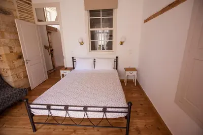 a bedroom with two beds with white walls and wooden floors at Green Door Apartment in Chania Town