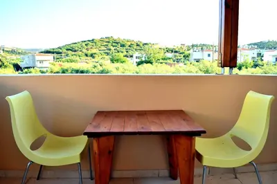 two chairs and a wooden table in front of a window at Almyrida sea view house in Almirida