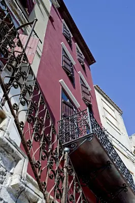 a red building with a gate and a balcony at Mosaic Venetian Harbour Suites in Chania Town