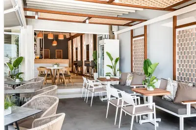 a restaurant with white chairs and tables and tables and chairs at Kalamaki Mare Suites in Kalamaki Chanion