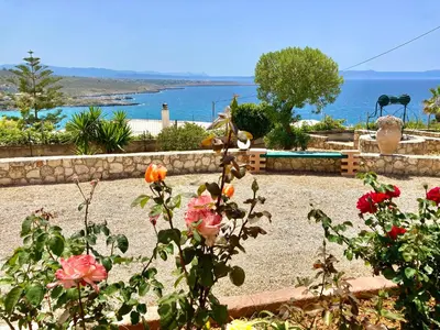 a garden with flowers and a view of the water at Seashore Apartments in Chorafakia