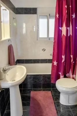 a bathroom with a sink and a toilet and a shower curtain at Seashore Apartments in Chorafakia