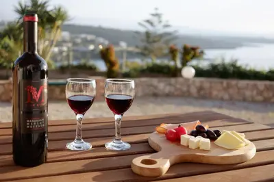 a bottle of wine and two glasses of wine and cheese at Seashore Apartments in Chorafakia