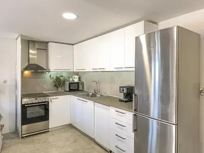 a kitchen with white cabinets and a stainless steel refrigerator at Charming Old Tannery House with Spacious Veranda and Stunning Sea View! in Chania Town