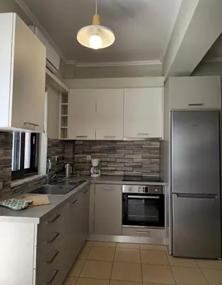 a kitchen with white cabinets and stainless steel appliances at Emily's House in Kissamos