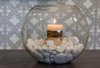 a candle sitting in a glass vase with rocks at BO Home in Souda