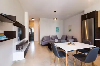 a kitchen and a living room with a table and chairs at Ethereal Apartments Chania in Souda