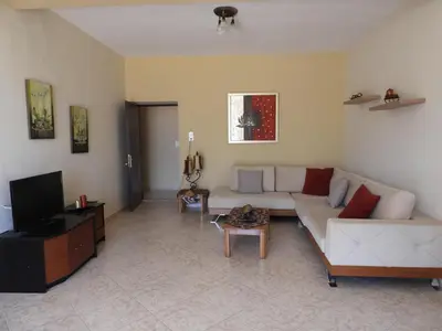 a living room with a white couch and a tv at Chrissi's house with garden and sea view Zerviana in Kissamos